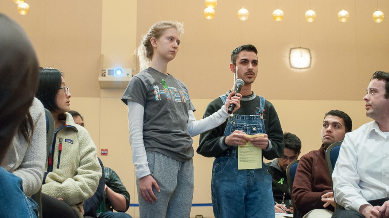 Audience member speaking into a microphone at the town hall.