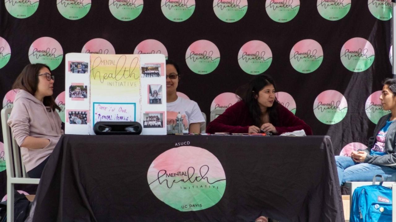 Mental Health Initiative team members sitting at our promotion table during Mental Health Awareness Month.