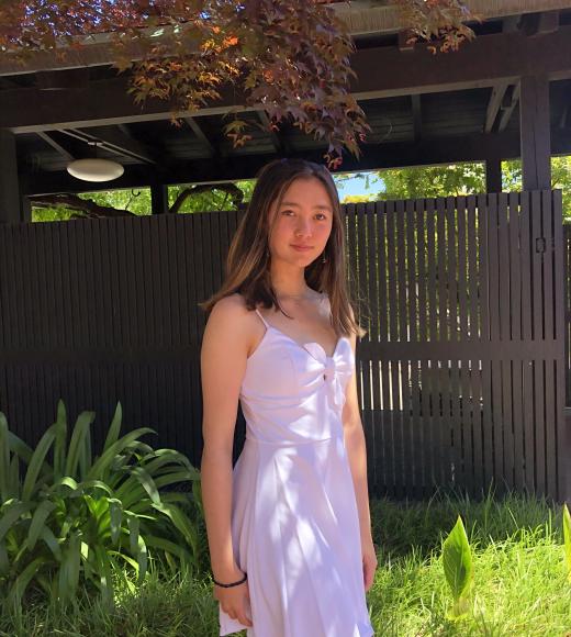 Portrait photo of Aya Clear in a purple dress with a green nature background