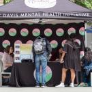 Student surround the Mental Health Initiative table for Mental Health Awareness Month activities.