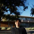 Portrait photo of Adam Cha wearing black in front of UC Davis building