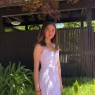 Portrait photo of Aya Clear in a purple dress with a green nature background