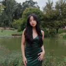 Portrait photo of Emerald Hue in a green dress with a nature background